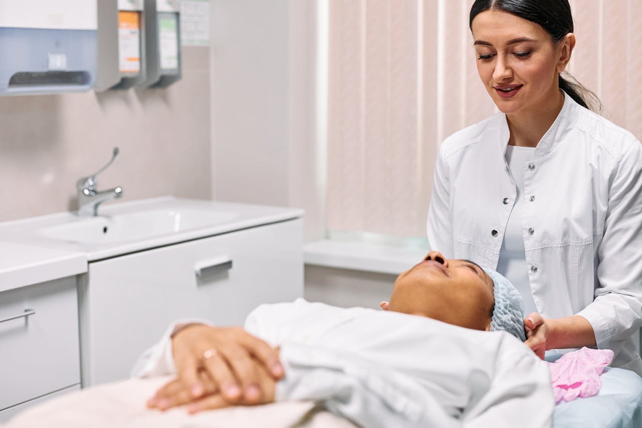 A beautician providing skincare treatment to a woman in a clinic setting, focusing on care and relaxation.